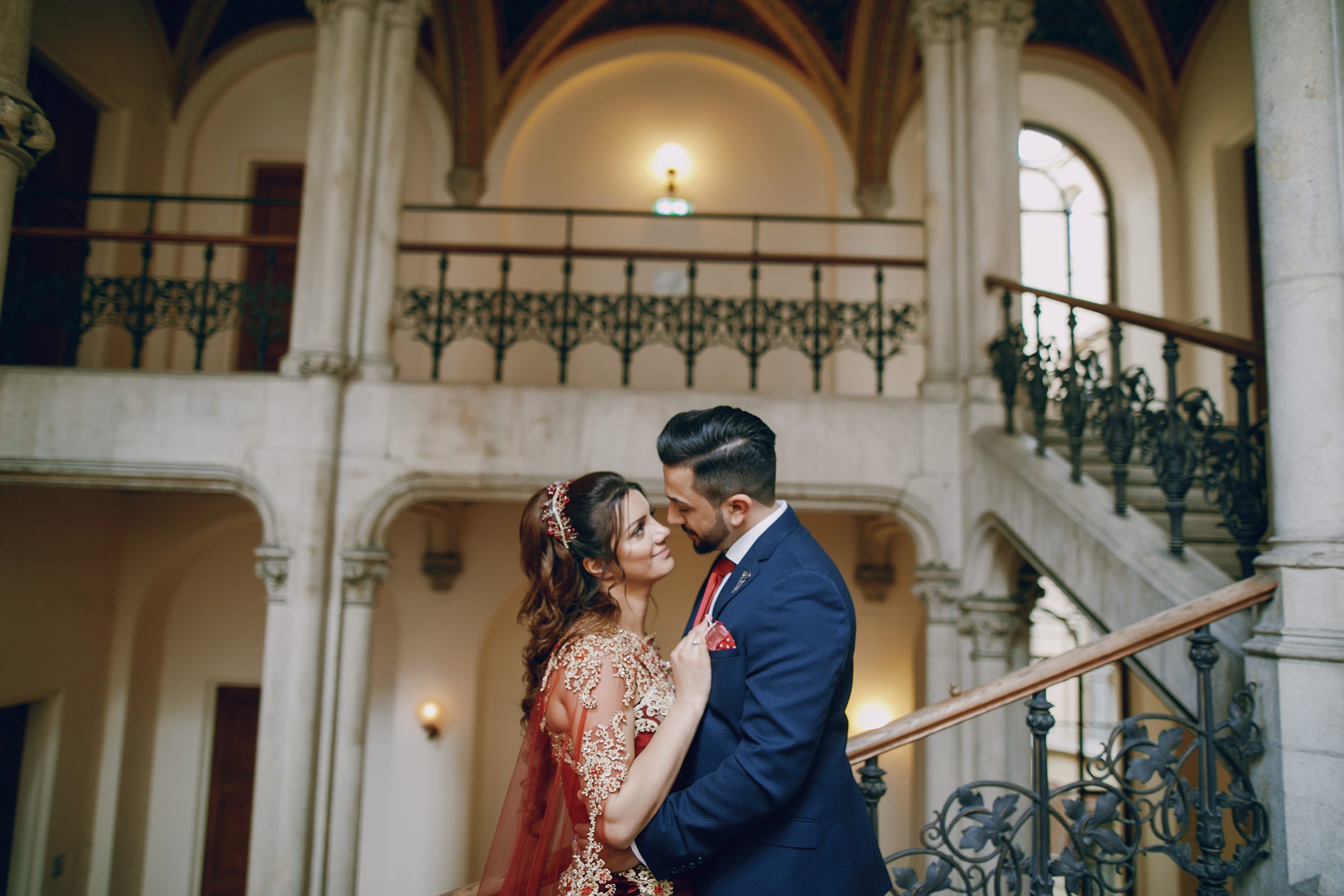 Beautiful woman in a long red dress walks around the city with her husband in a blue suit and with a beard