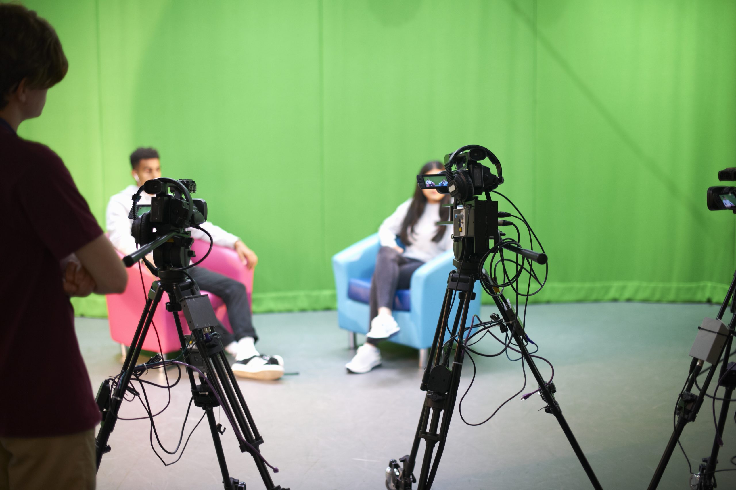 Young male and female college students practicing in TV studio with green screen
